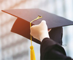 hand holding black mortarboard with gold tassel