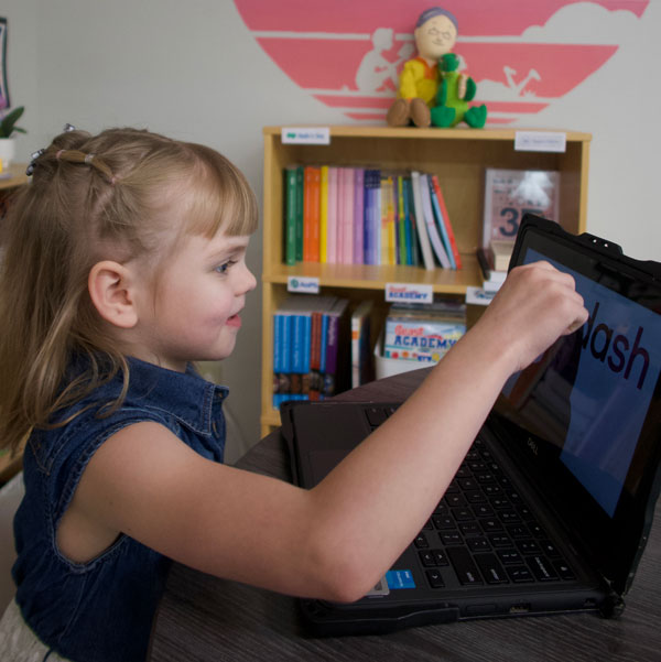 Girl sitting in front of an open Chromebook