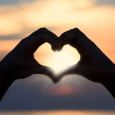 takecare photo of a silhouette of two hands making the shape of a heart against the background of a sunset<br />