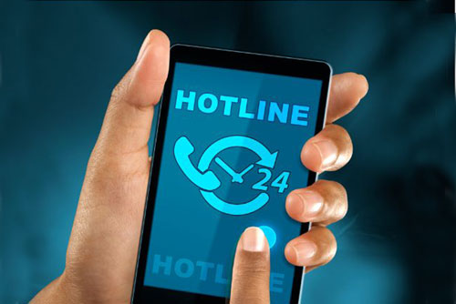 photo of hand holding a phone with the word hotline on it against a dark blue background
