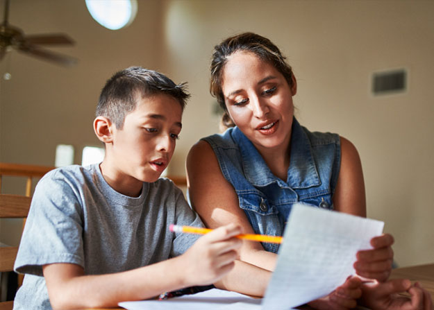 woman and a boy sitting together at a table and looking at a piece of paper held in front of them