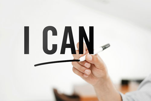 photo of a hand holding a pen writing the words I CAN