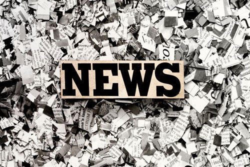 photo of the word NEWS in block letters on top of a pile of ripped newsprint