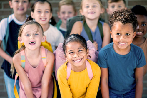 photo of kids with backpacks smiling at the camera
